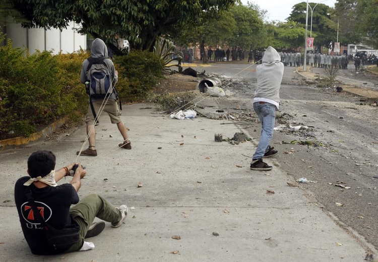 fot. Carlos Garcia Rawlins / Reuters / 27 lutego 2014  Caracas, Wenezuela  Demonstranci używają procy przeciwko Gwardii Narodowej.